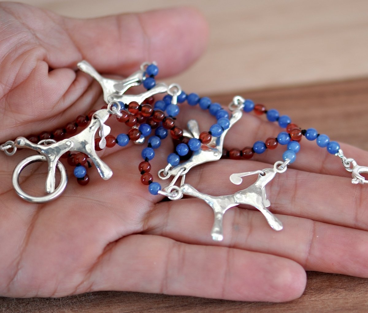 Handmade red and blue agate bead necklace with four articulated sterling silver dog charms, made in Barcelona