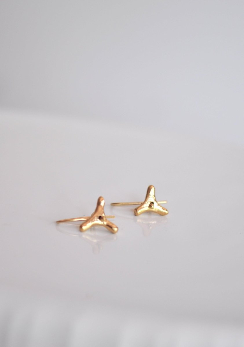 a pair of tiny gold earrings on a white surface