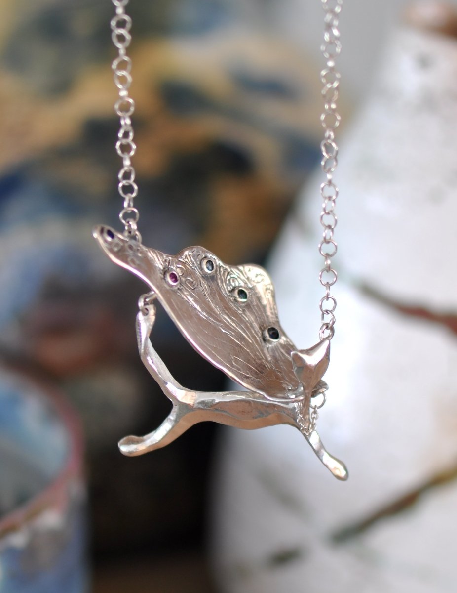 Handcrafted sterling silver necklace, whimsical cat pendant with a textured, wing-like cape, hanging on a silver chain.