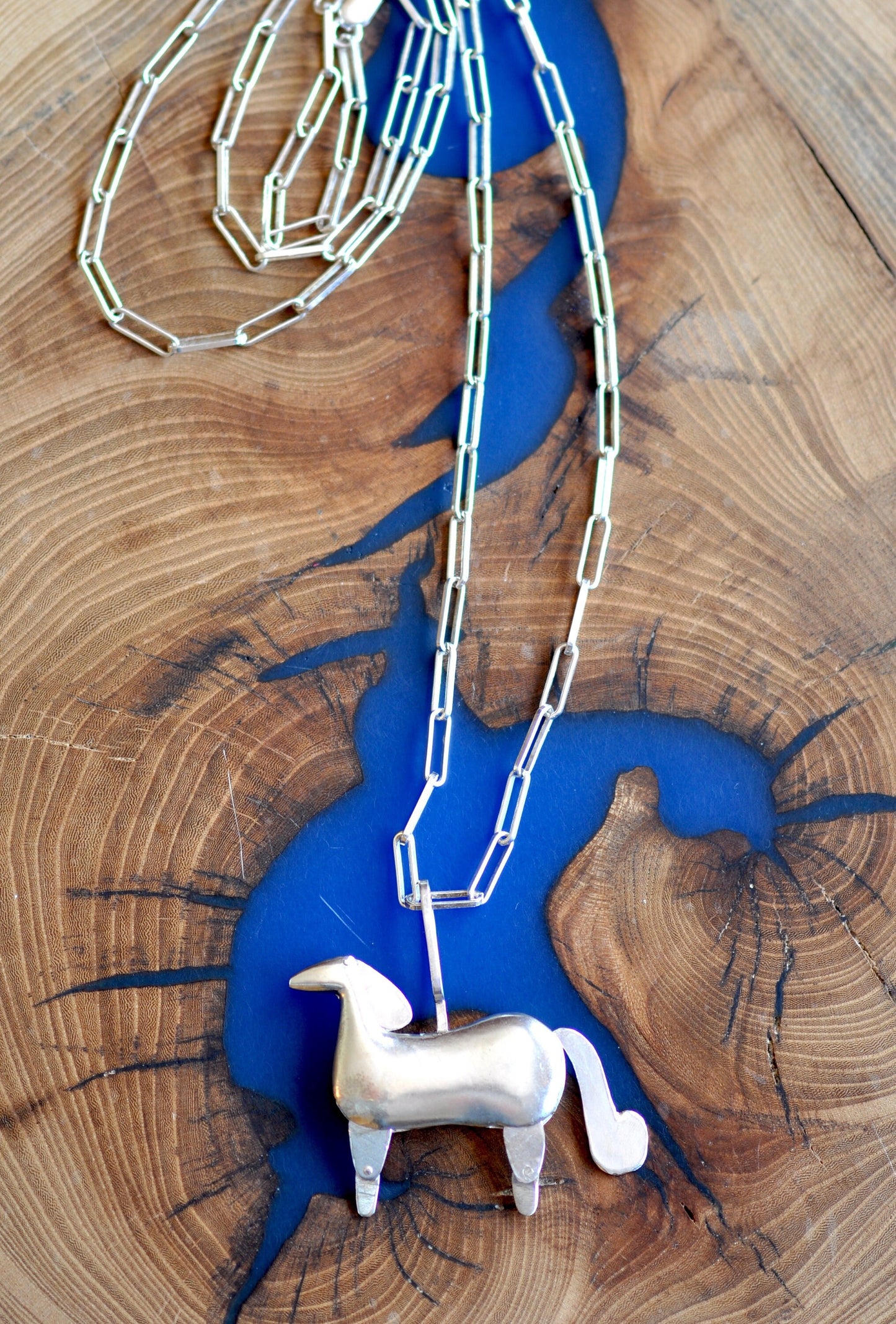 a toy horse on a chain on a wooden table