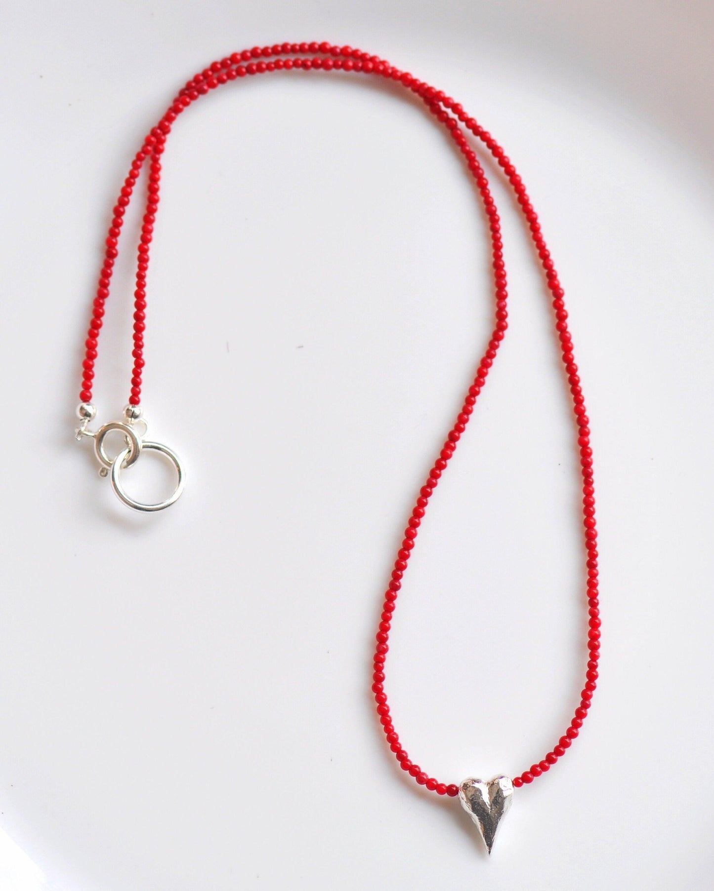 a red beaded necklace on a white plate