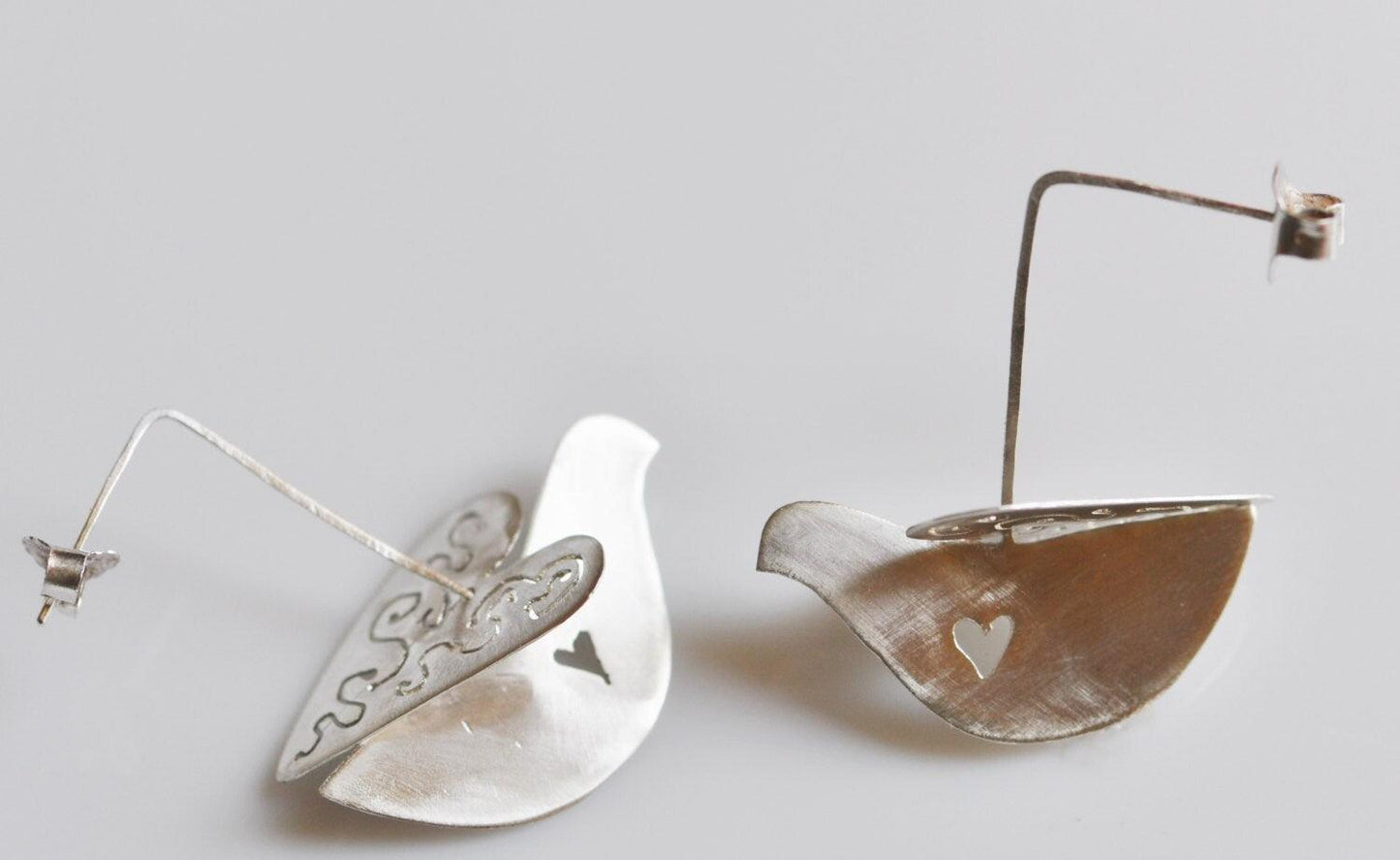 Handmade sterling silver dove dangle earrings with cut-out heart detail, whimsical bird jewelry
