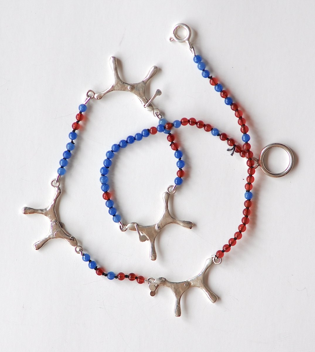 Handmade red and blue agate bead necklace with four articulated sterling silver dog charms, made in Barcelona