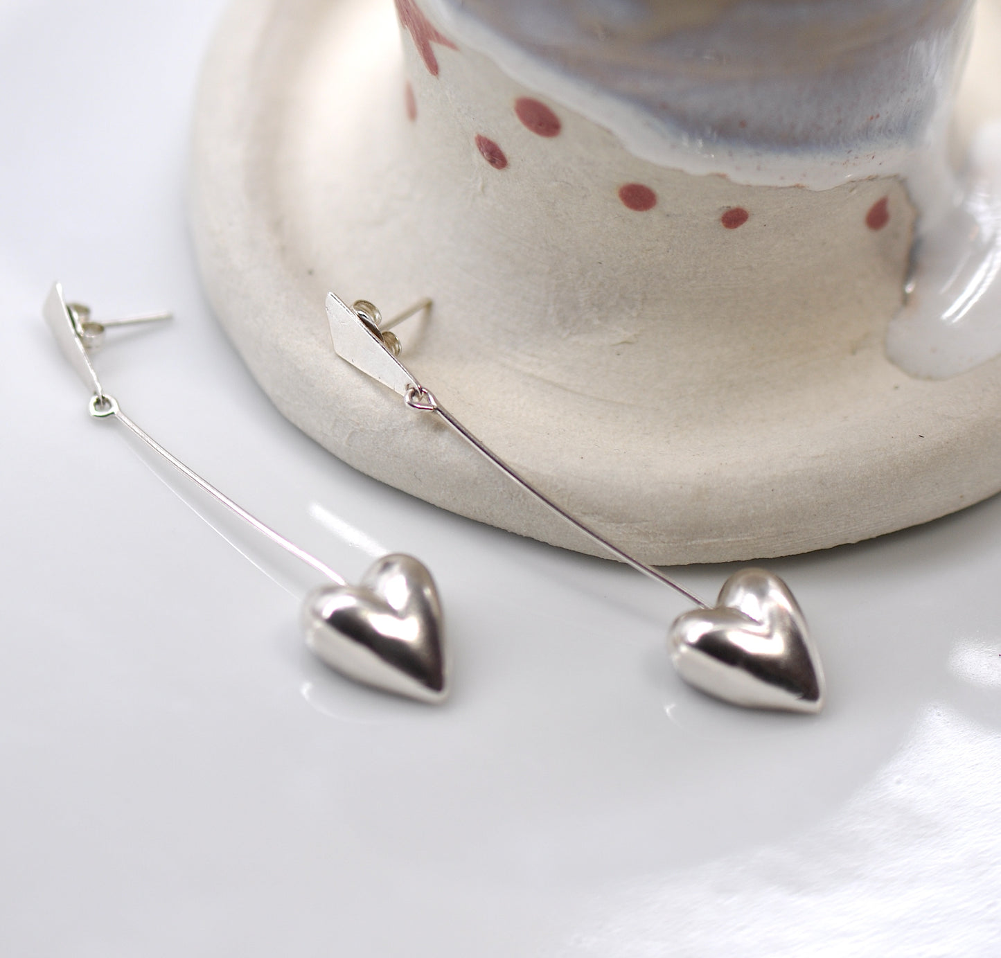 A pair of sterling silver dangle earrings in the shape of half hearts