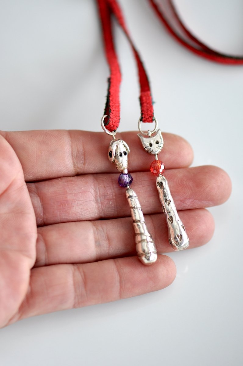 Handmade silver cat and dog charm lariat necklace on red cord with heart clasp, whimsical animal jewelry, made in Barcelona