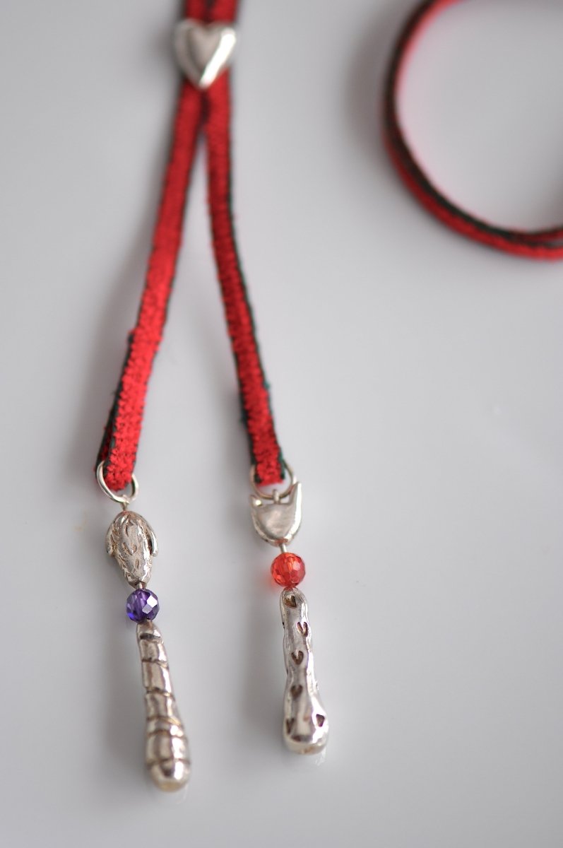 Handmade silver cat and dog charm lariat necklace on red cord with heart clasp, whimsical animal jewelry, made in Barcelona