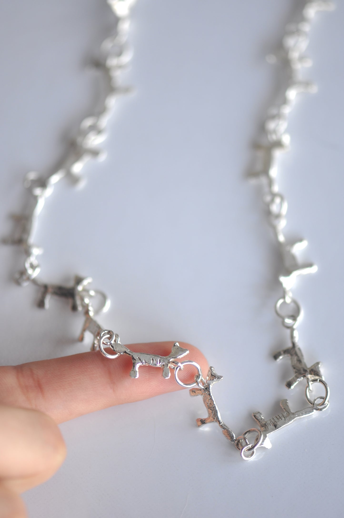 A long silver necklace with small cat links