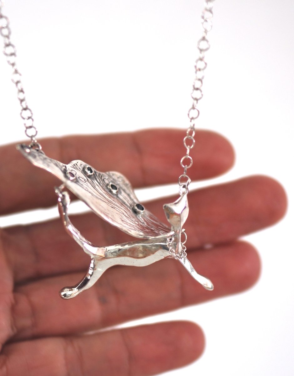Handcrafted sterling silver necklace, whimsical cat pendant with a textured, wing-like cape, hanging on a silver chain.