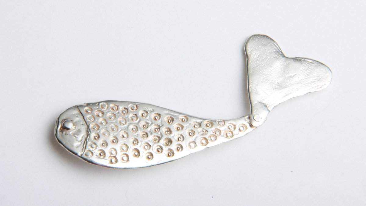 a silver fish brooch with a heart on it