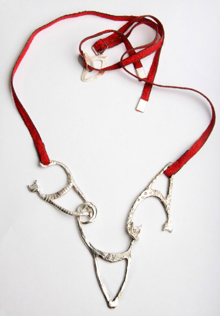 a silver necklace with a red ribbon on a white background