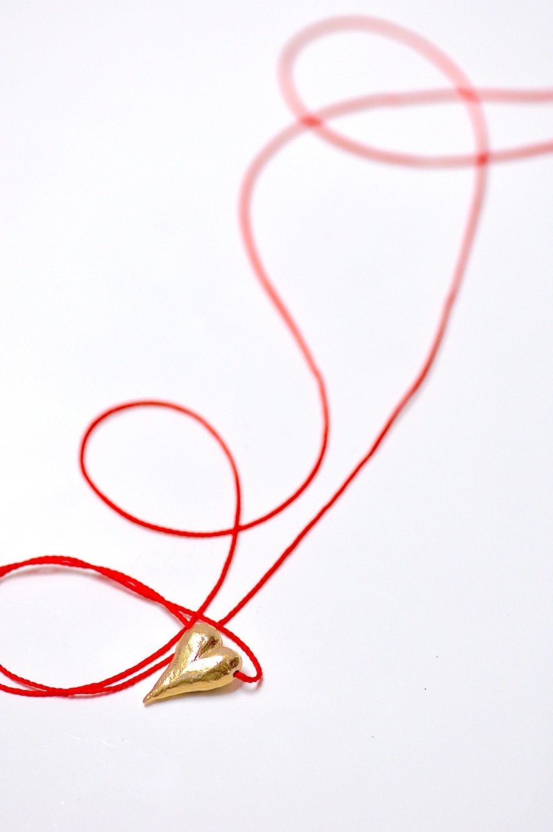 a piece of red string with a gold object on it