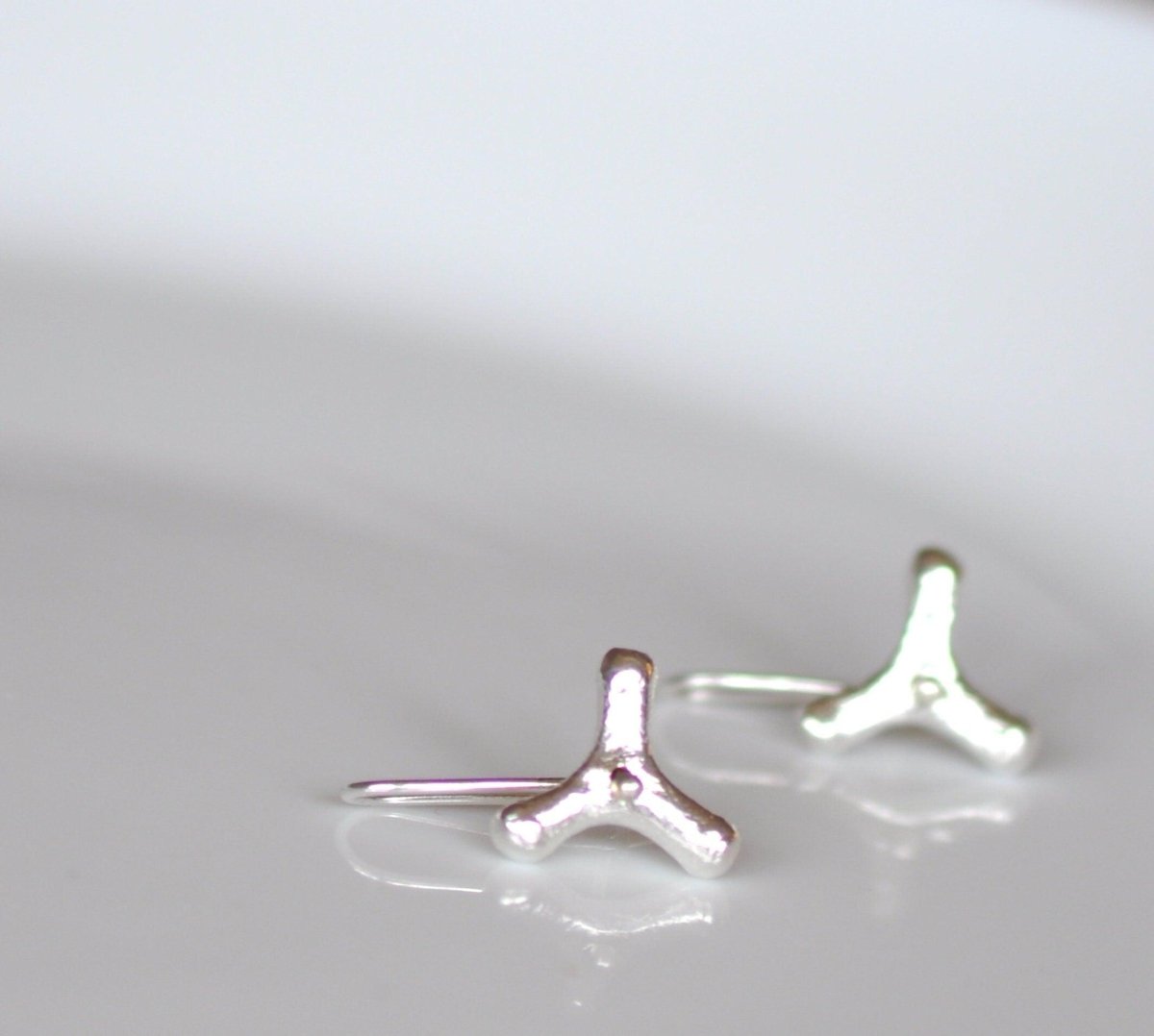 Handmade sterling silver spinning flower earrings with abstract rotating design, whimsical minimalist jewelry